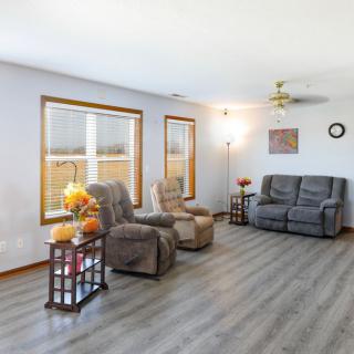 A cozy living room with recliners and a sofa, featuring large windows and stylish decor.