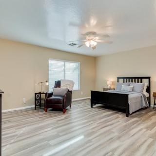 Spacious bedroom with modern decor, featuring a bed, chair, and a large window.