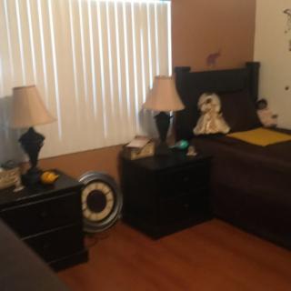 A cozy bedroom with nightstands and lamps beside the bed, featuring wooden flooring and window blinds.