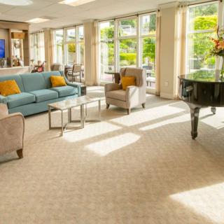 A bright and spacious living room with comfortable seating and a grand piano.