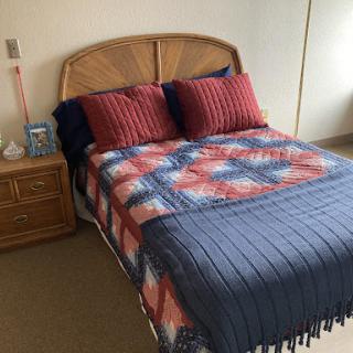 A neatly arranged bedroom featuring a comfortable bed with decorative pillows and a cozy blanket.