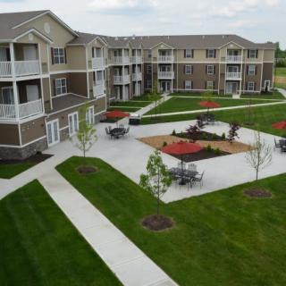 A well-maintained apartment complex with outdoor seating and landscaped green areas.