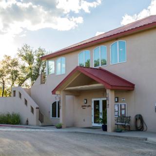 A two-story building with a modern entrance and outdoor staircase under a partly cloudy sky.