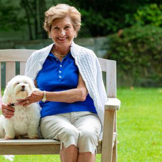 A woman sitting on a bench with her dog in a park.