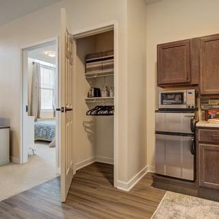A modern kitchen with an adjoining bedroom and an open closet door.