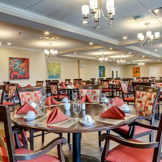 An elegant dining room with neatly arranged tables and vibrant red napkins.