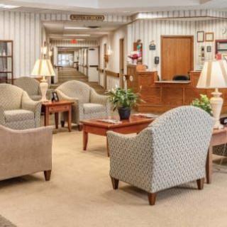 A comfortable lobby area with chairs and sofas, featuring a reception desk in the background.
