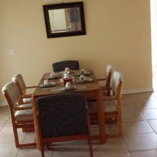 A dining room with a table set for four, featuring a wall-mounted mirror.