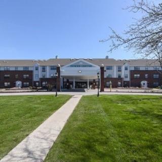 A large building with a central entrance and a well-maintained lawn in front.