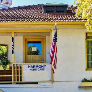 A house with a porch displaying a 'Harmony Home Care' banner and an American flag.