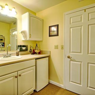 A cozy bathroom with a sink, mirror, and cabinetry against yellow walls.