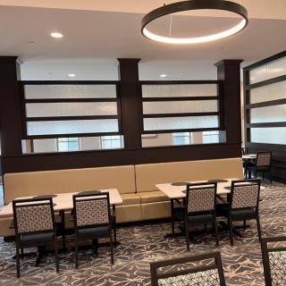 A modern dining area with neatly arranged tables and chairs, featuring contemporary lighting and design elements.