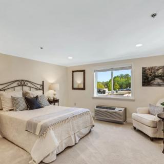 A cozy bedroom with a comfortable bed, armchair, and window view.