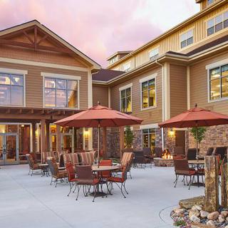 An inviting patio area with tables and umbrellas in front of a residential-style building.