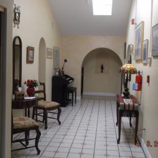 A well-lit hallway with furniture and decor, featuring a tiled floor and an archway at the end.