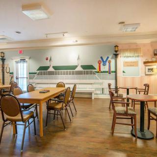 A cozy dining area with wooden tables and chairs, decorated with a mural and warm lighting.