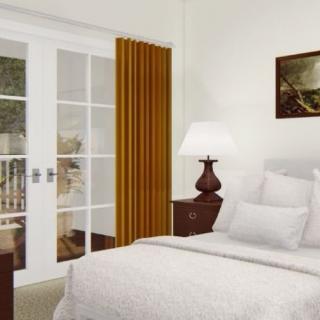Cozy bedroom with a neatly made bed, bedside lamp, and sliding glass doors.