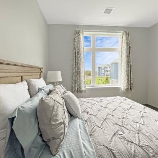 A cozy bedroom with a neatly made bed and sunlight streaming through the window.