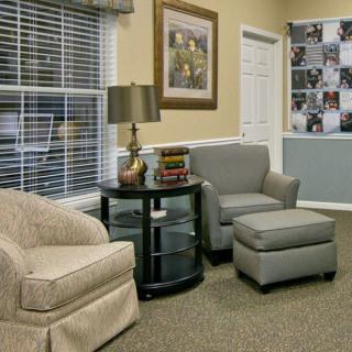 A cozy living room setting with armchairs, a lamp, and decorative elements.