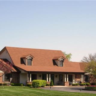 A suburban house with a red roof and well-maintained lawn.