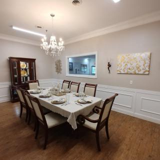 A dining room with a set table, chandelier, and wooden flooring.
