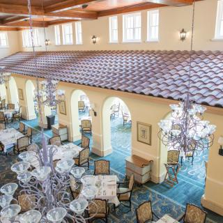 An elegant dining area with chandeliers and neatly arranged tables and chairs.