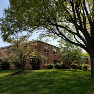A serene view of a brick building surrounded by lush greenery and trees.