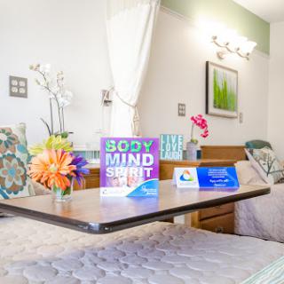 A cozy hospital room designed to promote well-being with floral arrangements and wellness signage.