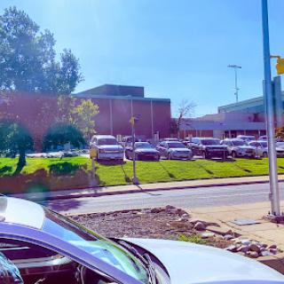 A bright day at a parking lot with vehicles lined up in front of a building.