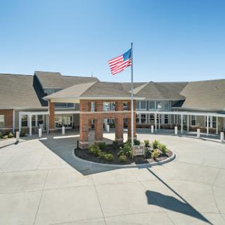 The entrance of a well-designed building with an American flag waving in front.