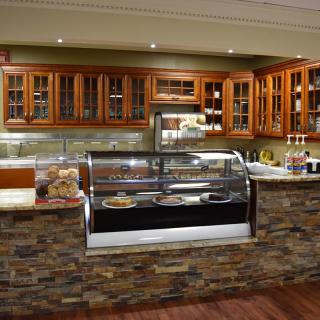 A cozy cafe with a stone facade counter and a display case filled with pastries.