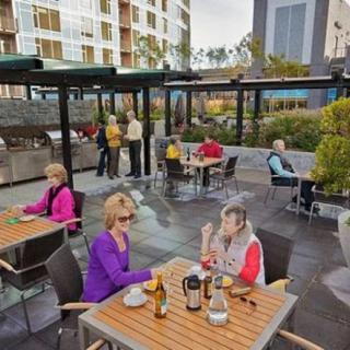 People enjoying a relaxed meal and conversation on an outdoor patio in an urban setting.
