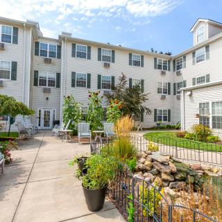 A well-maintained courtyard with lush greenery in front of a multi-story residential building.