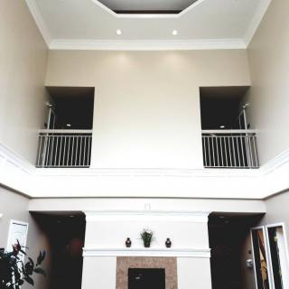 A modern living room with a high ceiling and balcony overlooking a central fireplace.
