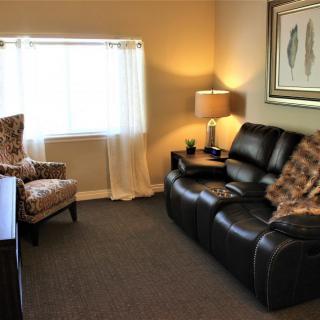 A cozy living room with a leather sofa, armchair, lamp, and decorative elements.