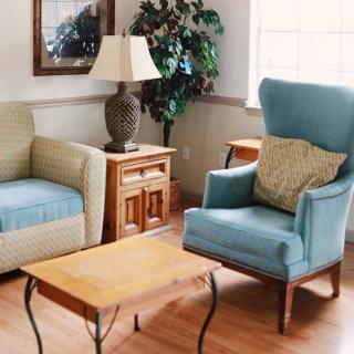 A cozy living room featuring a mix of comfortable armchairs, a wooden coffee table, and warm decor.
