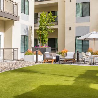 A modern apartment courtyard with a well-manicured lawn and outdoor seating area.