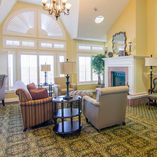A spacious and well-lit living room featuring elegant furniture, a cozy fireplace, and large windows.