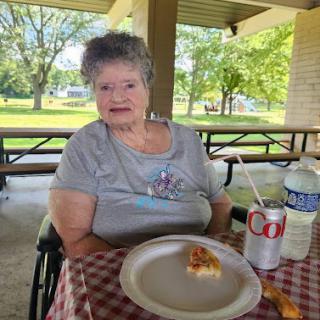 A woman enjoying a meal outdoors at a picnic table.