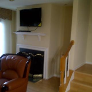 A cozy living room with a fireplace, wall-mounted television, and nearby stairs.