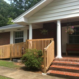 A brick house with a wooden accessibility ramp and porch.