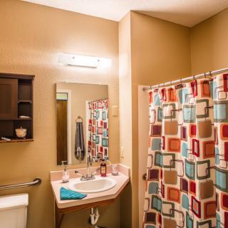 A cozy bathroom with a colorful shower curtain, mirror, and sink.