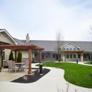 A well-maintained courtyard with outdoor seating and a pergola, adjacent to a residential building.