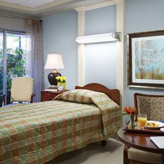 A cozy bedroom featuring a single bed, lamp, and decorative elements.