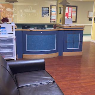 A view of a modern reception area with a black sofa and a blue front desk.