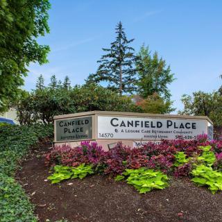 Entrance sign to Canfield Place surrounded by vibrant landscaping and greenery.
