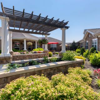 Beautiful garden patio with a pergola and vibrant landscaping on a sunny day.