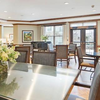 A well-lit dining area with tables, chairs, and decorative flowers.