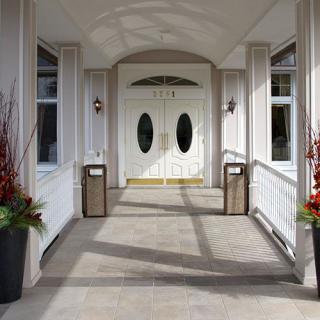 Elegant entrance with double doors and potted plants on either side.