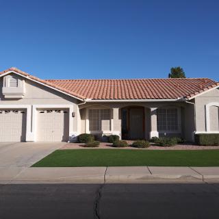 A charming single-family home with a tiled roof and well-maintained lawn.